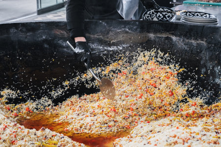 man cook puts cooked Uzbek pilaf from cauldron on plate. Traditional Oriental Arabic cuisine....