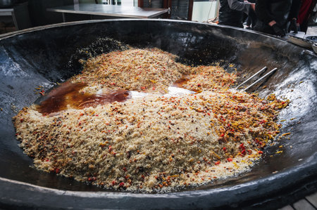 oriental dish of Uzbek cuisine is rice pilaf in a huge cauldron in kitchen of an Asian restaurant in...