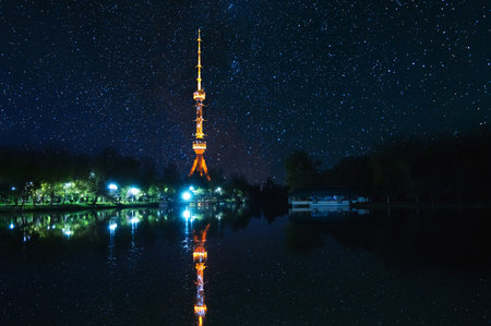 television TV tower illuminated in Tashkent in Uzbekistan with a reflection in water of river on background of a dark blue starry night skyの写真素材