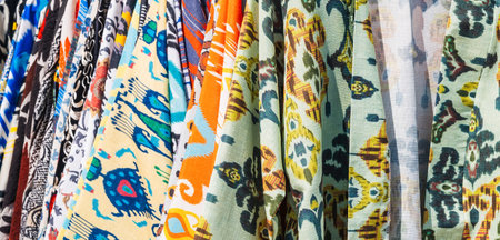 Uzbek dresses and female clothes made of silk and cotton with a colorful pattern at oriental bazaar...