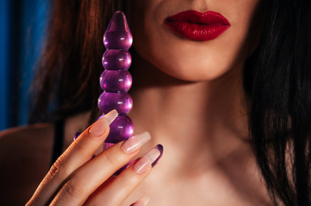 sexy girl holds a silicone butt anal plug in hands for masturbation and orgasm. A woman in lingerie with a sex toy for anal orgasm in bedroomの写真素材