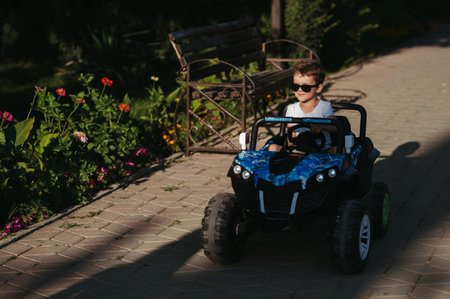 boy rides in toy mini car in park in summerの写真素材