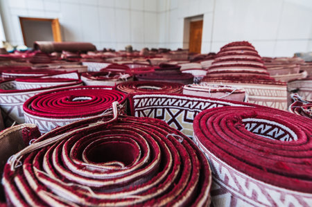 stack of rolled up traditional old Uzbek red carpets at oriental bazaar in Uzbekistan closeupの写真素材