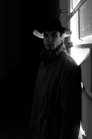 dark dramatic silhouette of a man in a hat and raincoat at night on the streetの写真素材