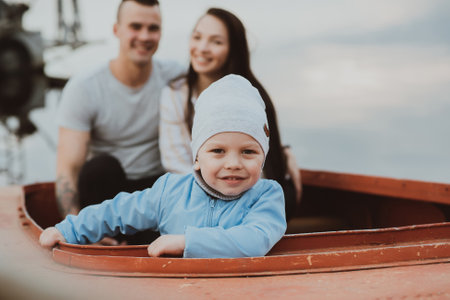 young son and a happy couple of parents sit in a boatの写真素材