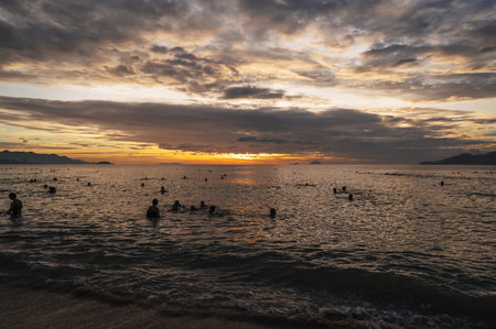 The sea with swimming Asian Vietnamese people in morning at dawn in Nha Trang. Nha Trang, Vietnam - July 19, 2024のeditorial素材