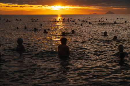 Silhouettes of people swimming in the sea in morning at dawn on Nha Trang beach. Nha Trang, Vietnam - July 19, 2024のeditorial素材