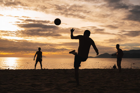 Silhouettes of Vietnamese men playing beach soccer in the morning by sea at sunrise in Nha Trang. Nha Trang Vietnam - July 19, 2024のeditorial素材