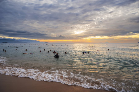 Vietnamese Asian people swim in sea in the morning on Nha Trang beach. Nha Trang, Vietnam - July 18,...