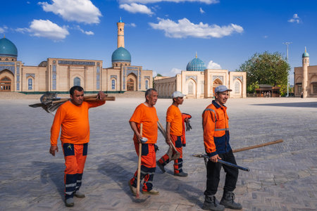 group of Uzbek male janitors in orange uniforms with shovels on street in spring on square of the Hazrati Imam architectural complex. Tashkent, Uzbekistan - April 17, 2024のeditorial素材