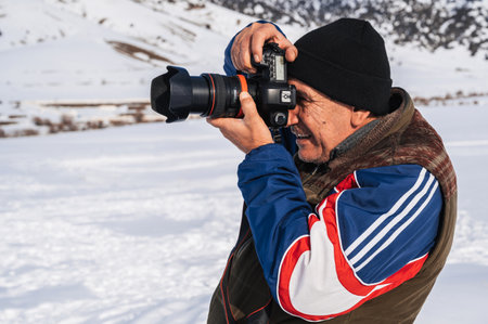 elderly man with camera, mountain hiker admiring mountain winter landscape.の写真素材