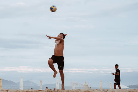 Asian Vietnamese man serves the ball in a beach volleyball game on the beach by sea. Nha Trang, Vietnam - July 21, 2024のeditorial素材