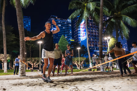 male acrobat trains a slackline while standing on a tightrope in summer on beach in Vietnam. Nha Trang, Vietnam - July 21, 2024のeditorial素材