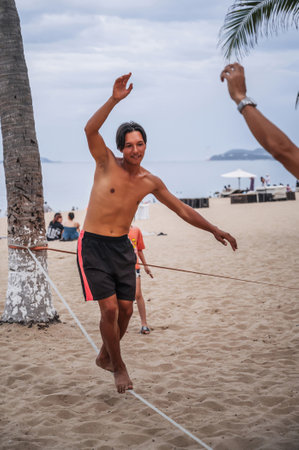 A young man trains slackline tightrope walking on beach in Vietnam in the summer. Nha Trang, Vietnam - July 25, 2024のeditorial素材