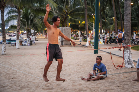A young man trains slackline tightrope walking on beach in Vietnam in the summer. Nha Trang, Vietnam - July 25, 2024のeditorial素材
