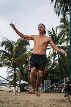 A young man trains to walk slackline rope on the beach in summer. Nha Trang, Vietnam - July 29, 2024