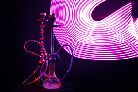 two hookahs with pipes and bowls and a flask of water with purple neon lighting