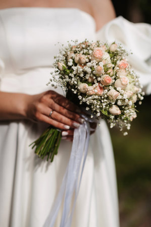 wedding bouquet of white roses in the hands of the brideの写真素材