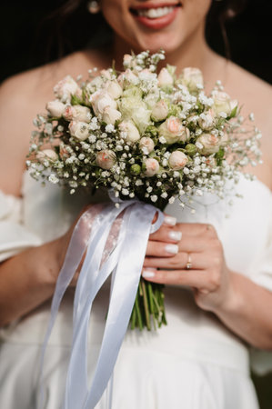 wedding bouquet of white roses in the hands of the brideの写真素材