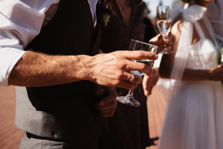 man groom holds a glass of champagne in hand at a wedding ceremonyの写真素材