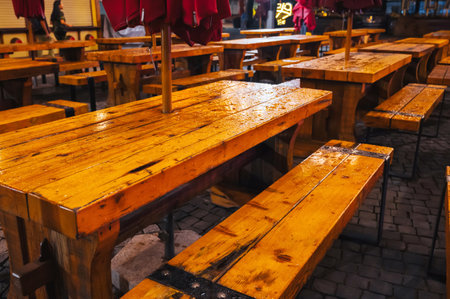 wooden tables and benches in street cafe in Europe in eveningの写真素材
