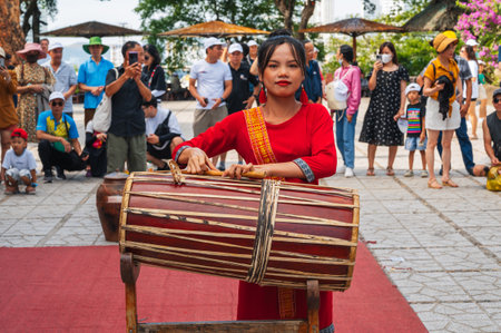 Young Vietnamese woman in a red dress playing a traditional drum at Po Nagar Cham Towers in Nha Trang in Asia. Nha Trang, Vietnam - August 8, 2024のeditorial素材
