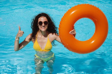 young beautiful happy girl in sunglasses relax in an inflatable circle in pool at a hotel on...