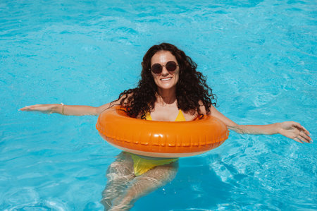 young girl in sunglasses relax in an inflatable circle in pool at a hotel on vacation at resort in...