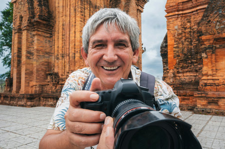 happy elderly man tourist traveling photographer with camera takes pictures of landmarks at ancient Po Nagar Cham Towers in Nha Trang in Vietnam in Asiaの写真素材