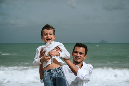 happy father with child boy son playing on the beach by the sea in summerの写真素材