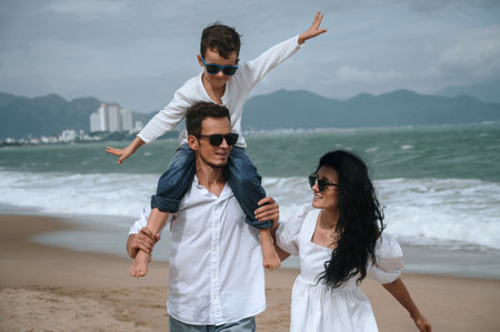 happy family with a child boy son walking along the beach by sea in summer on vacation