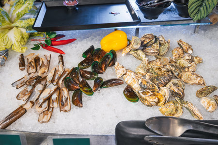Asian seafood in buffet at hotel restaurant in Asia. Fresh oysters and mussels sea clams on ice at a night market in Vietnamの写真素材