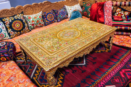 beautiful patterned traditional Uzbek dastarkhan table, colorful pillows and a vintage carpet in...