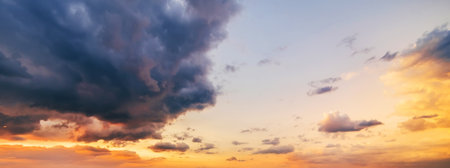background with an orange sunset on cloudy sky with blue clouds. Panorama of sky at sunriseの写真素材