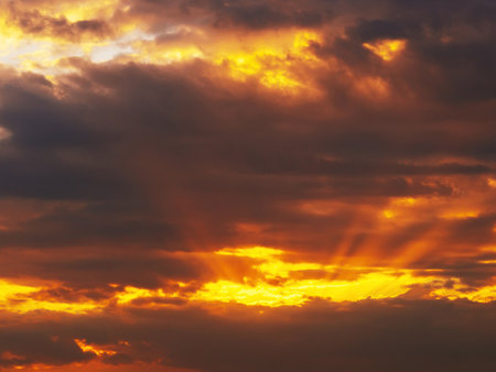 orange sunset with sunlight on cloudy sky. Background with sky and clouds in summer eveningの写真素材