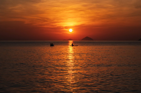 Silhouettes of people floating on sap boards in sea in the evening at sunset in summer
