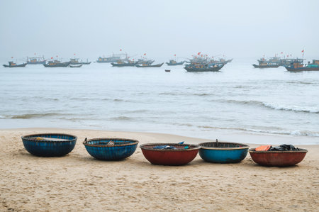 Vietnamese traditional round baskets boats Thung Chai on the beach and ships at sea in a fishing village in Vietnamの写真素材