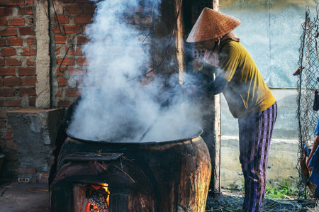 Vietnamese woman in a traditional straw hat works in reed dyeing workshop for production of woven mats in Vietnamの写真素材
