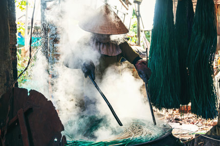 Vietnamese woman dyes reeds at a woven sleeping mat factory in Vietnamの写真素材