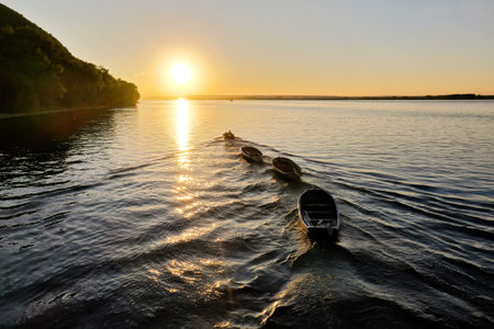 A line of boats peacefully floating on the calm surface of a body of water, creating a picturesque and serene scene.の写真素材