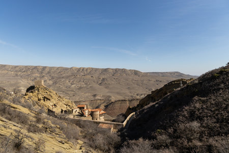 A lone house sits in the midst of a mountain range, nestled in the tranquil setting of the David Gareja monastery complex in Georgia.の写真素材