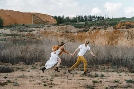 A man and a woman holding hands, running across the field.の写真素材