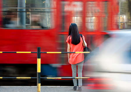 Young woman waiting at bus stop and city traffic  in motion blurの写真素材