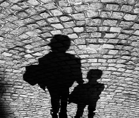 Shadow of an adult and a child on cobbled sidewalk in blak and whiteの写真素材