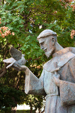 Sibenik, Croatia - August 18, 2017: Public statue of Saint Francis of Assisi holding a dove and a cross, in the park next to the church of Our Lady out of town in Sibenik, Croatiaのeditorial素材