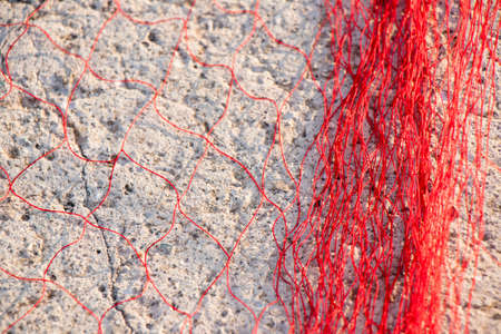 Red fishing net on stone pier in sunlightの写真素材