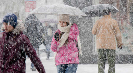 Belgrade, Serbia - December 15, 2018: One teenage girl walking under umbrella in heavy snowfall in...