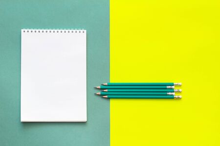 White wideopen blank clean notepad page and green pencils on yellow-green table.の写真素材