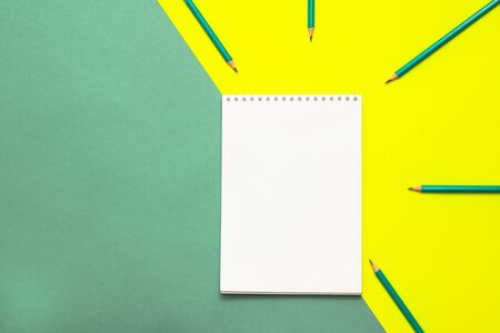White wideopen blank clean notepad page and green pencils on yellow-green table.の写真素材