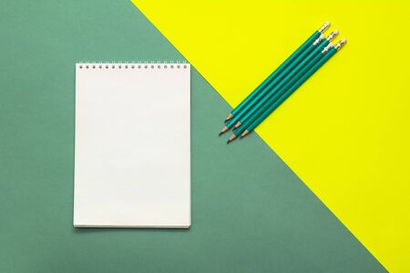White wideopen blank clean notepad page and green pencils on yellow-green table.の写真素材
